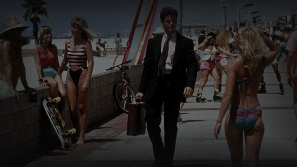 Still from Side Out (1990) — 16:9 still from Letterboxd (the 1200x675 crop variant), baked through scripts/bake_dark_photo.py at default factor, mean brightness 41.2 (in canon range, slightly above the 25-35 target but appropriate for a bright sunlit beach-boardwalk still).