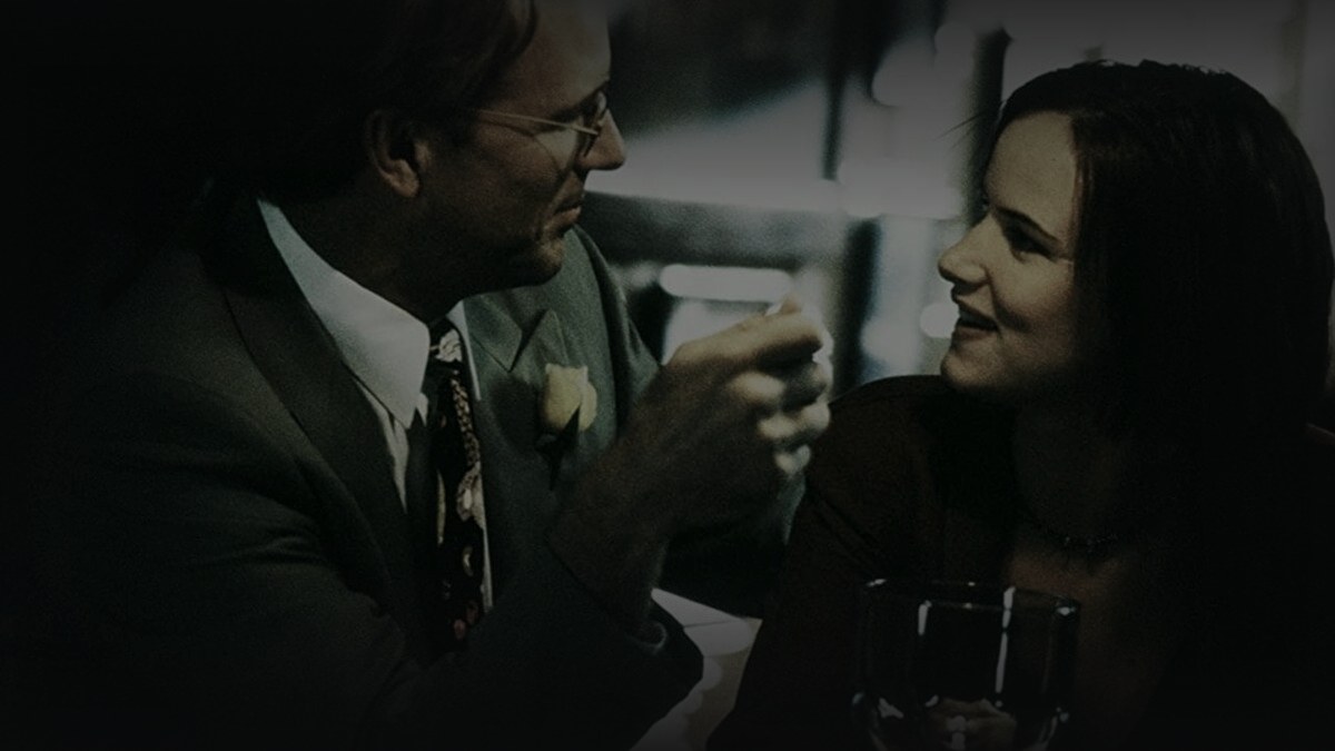 Still from The 4th Floor (1999) — 16:9 still from Letterboxd (the 1200x675 crop variant), baked through scripts/bake_dark_photo.py at default factor 0.45, output brightness 24.9